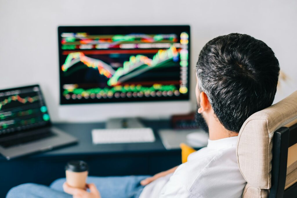 Caucasian businessman trading online, using computer technology, looking on stock exchange